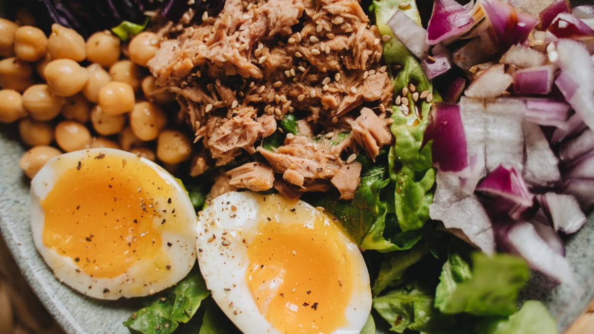 Close-up of a nutritious salad with tuna, soft-boiled eggs, and fresh vegetables.